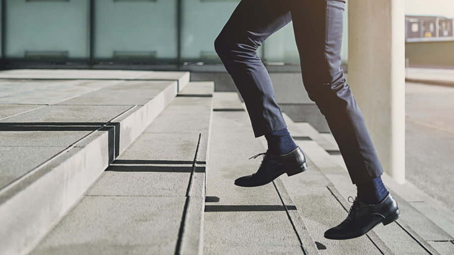 Gesch&auml;ftsmann geht eilig die Treppe hoch um p&uuml;nktlich zur Arbeit zu kommen