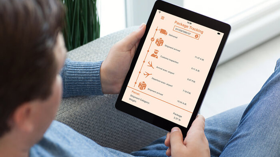 App Paket-Tracking, Mann sitzt auf Sofa mit Tablet