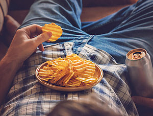 Binge Watchning: Mann liegt im Sessel mit Chips