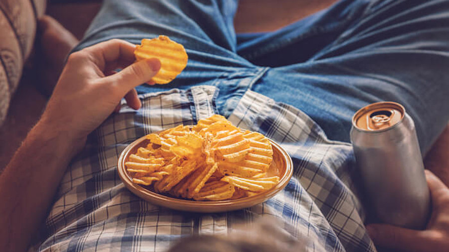 Binge Watchning: Mann liegt im Sessel mit Chips