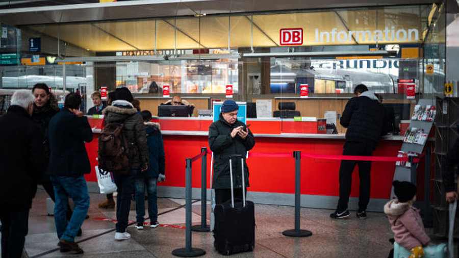 Reisende am Bahnhof vor einem Schalter der Deutschen Bahn