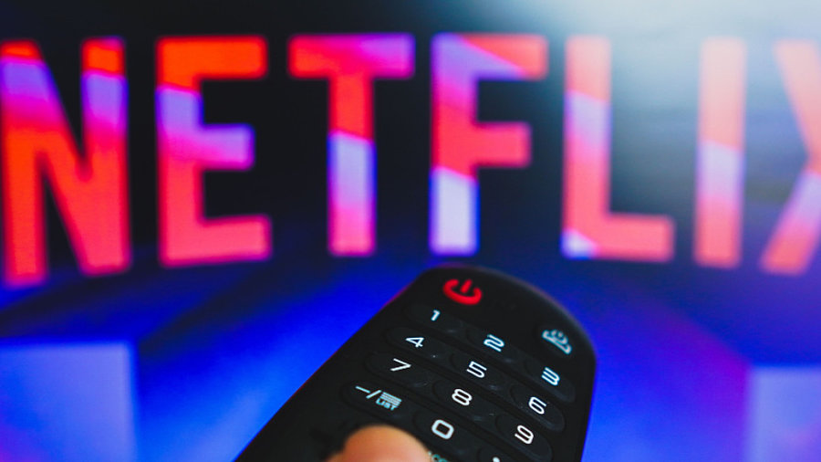 Netflix-Logo und Hand an TV-Fernbedienung