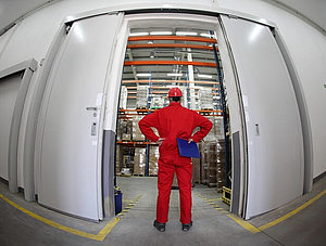 A fish eye view of a worker standing in the doorway of a modern industrial facility.