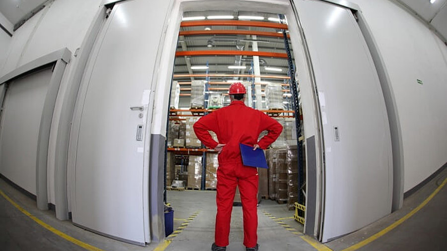 A fish eye view of a worker standing in the doorway of a modern industrial facility.