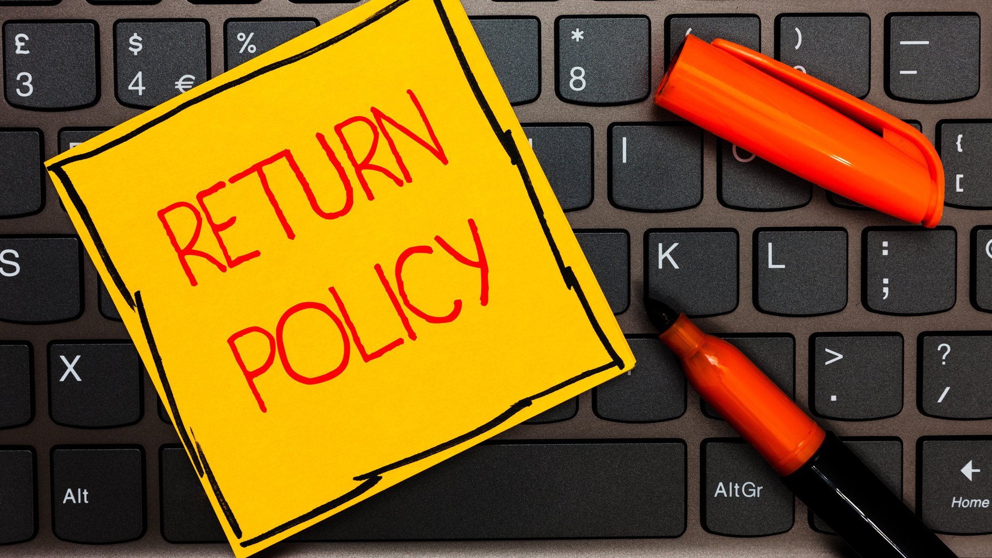 Auf einer Tatstur klebt ein Zettel mit "Return Policy"