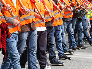 Streikende in Warnwesten laufen in einer Reihe