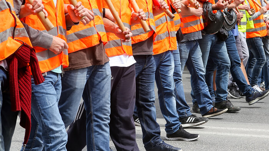 Streikende in Warnwesten laufen in einer Reihe