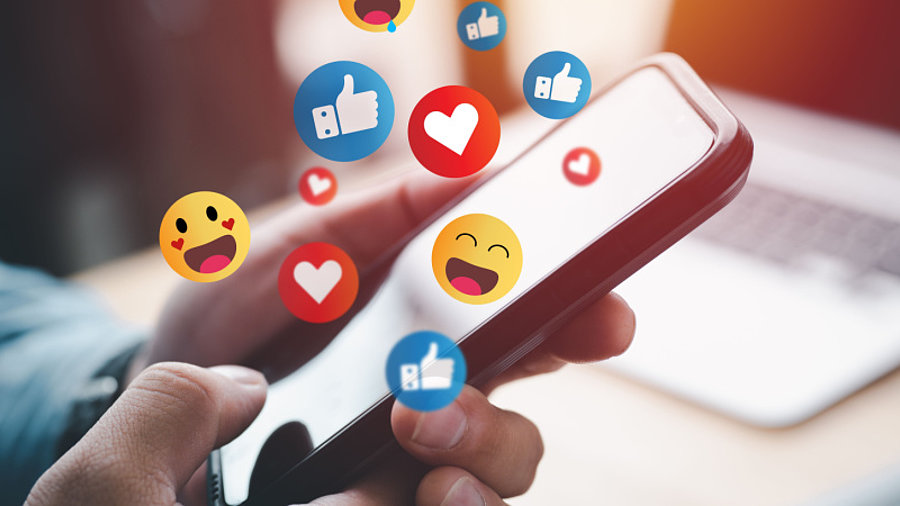 Mensch h&auml;lt Smartphone Emojis und Social Media Likes