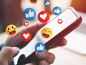 Mensch h&auml;lt Smartphone Emojis und Social Media Likes