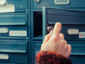 Frau öffnet Briefkasten