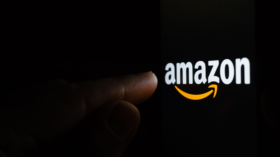 Finger zeigt auf Amazon-Logo vor schwarzem Hintergrund