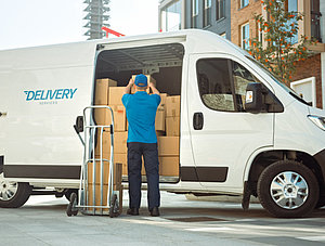 Zusteller mit Auto und Paketen