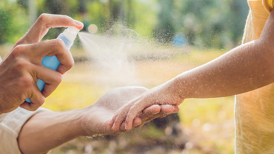 Person spr&uuml;ht Kind mit Spray ein