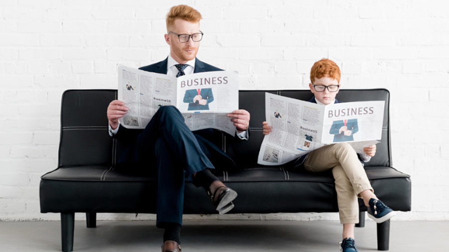 Vater und Sohn in Anz&uuml;gen mit Zeitung