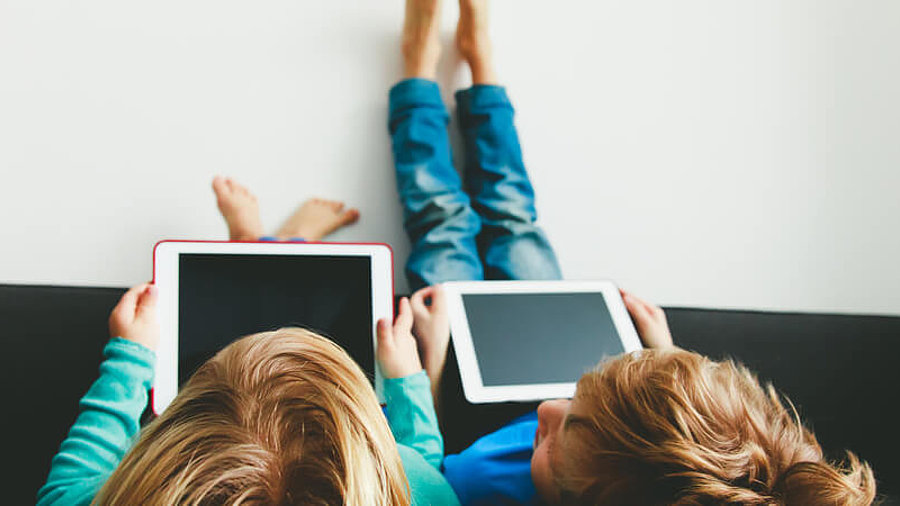 Kinder spielen im Bett auf dem Tablet