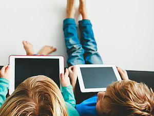 Kinder spielen im Bett auf dem Tablet