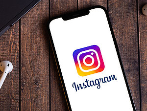 Instagram-Logo auf Smartphone. Neben dem Smartphone liegt ein Kopfh&ouml;rer