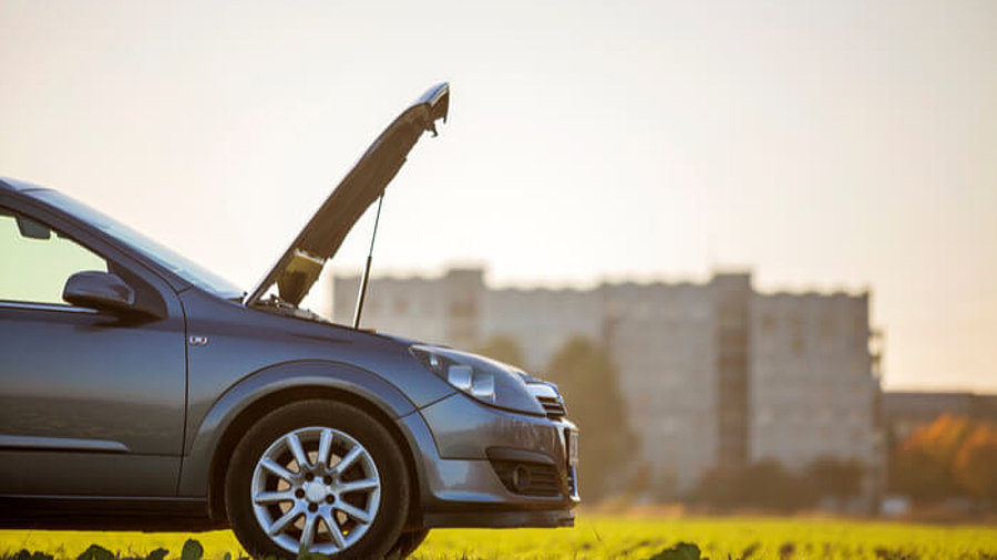 Auto hat Panne mit Stadt im Hintergrund.