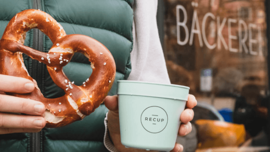 Frau mit Recup-Becher und Breze