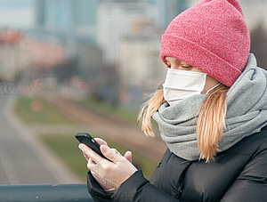 Frau mit Smartphone und Gesichtsmaske