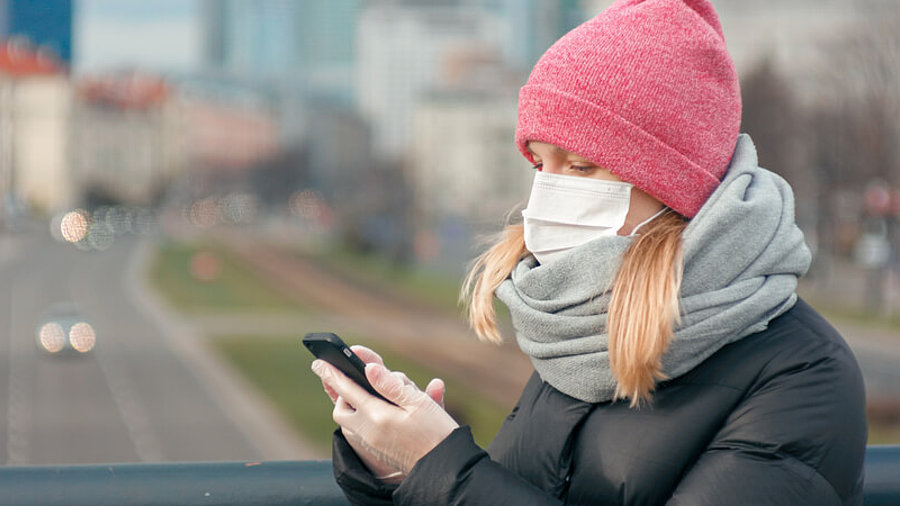 Frau mit Smartphone und Gesichtsmaske