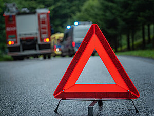 Rettungskräfte und Warndreieck an Unfallstelle