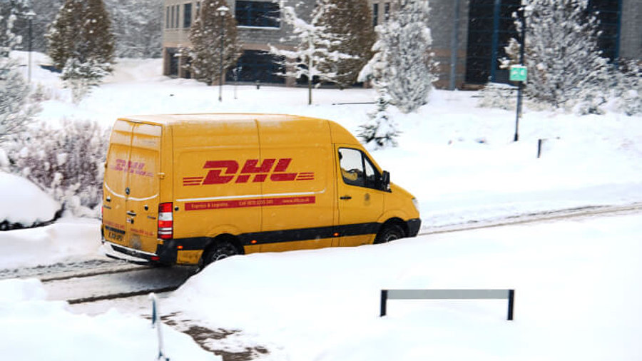 DHL-Lieferwagen fährt durch verschneite Straßen