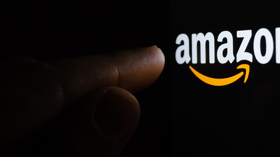 Finger ber&uuml;hrt Amazon-Logo dunkler Hintergrund