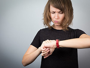 Frau schaut auf die Uhr mit verärgertem Gesichtsausdruck 