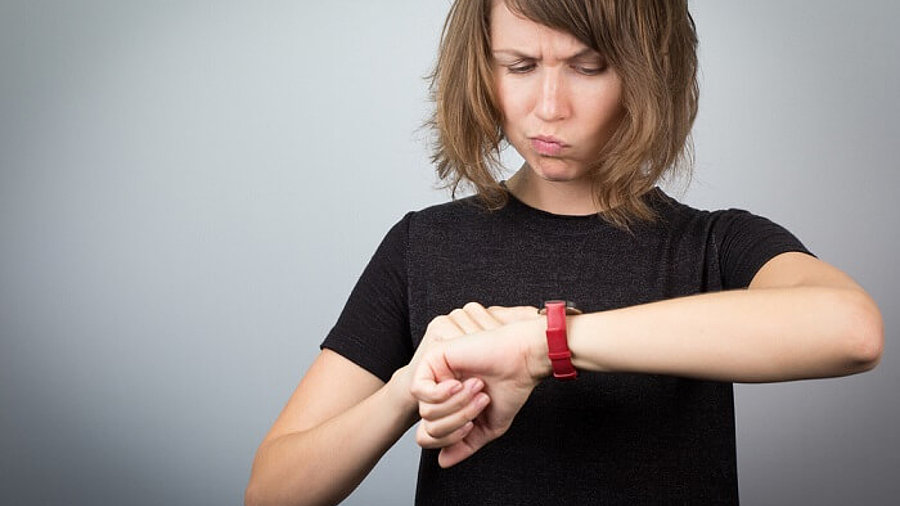 Frau schaut auf die Uhr mit verärgertem Gesichtsausdruck 