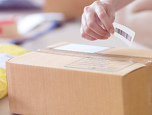 Person klebt Versandlabel auf Paket