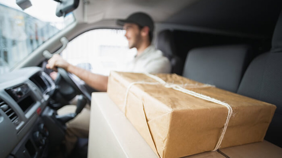 Paketbote im Auto mit Paketen auf dem Beifahrersitz