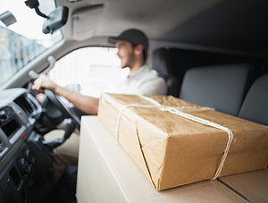 Paketbote im Auto mit Paketen auf dem Beifahrersitz