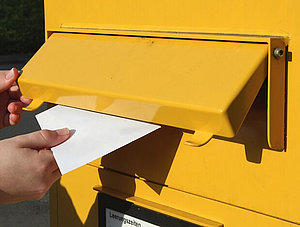 Brief wird in einen Briefkasten gesteckt