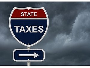 Schild vor bewölktem Himmel mit Aufschrift State Taxes