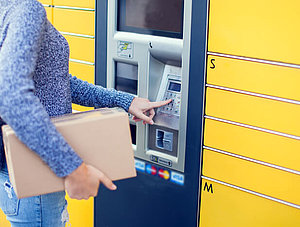 Frau mit Paket an Paketstation