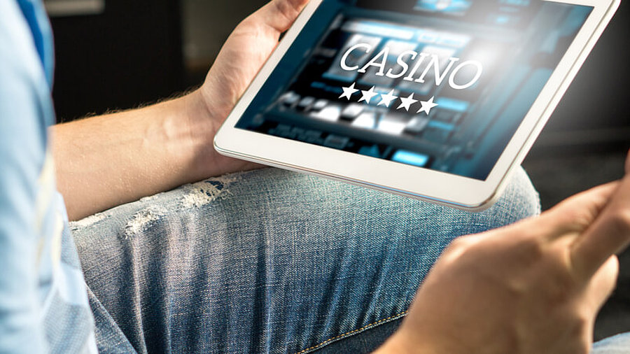 Mann, der am Tablet ein Online-Casino &ouml;ffnet.