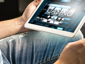 Mann, der am Tablet ein Online-Casino &ouml;ffnet.