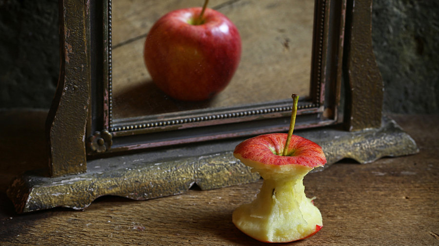 Verkehrtes Spiegelbild: Ein Apfel vor einem Spiegel