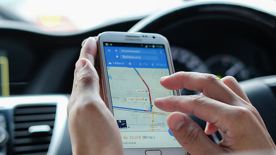 Frau nutzt Google Maps auf Smartphone im Auto