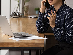 Frau am Laptop telefoniert