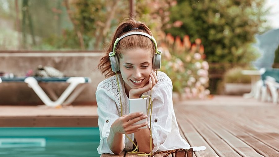 Lady hört Musik am Pool