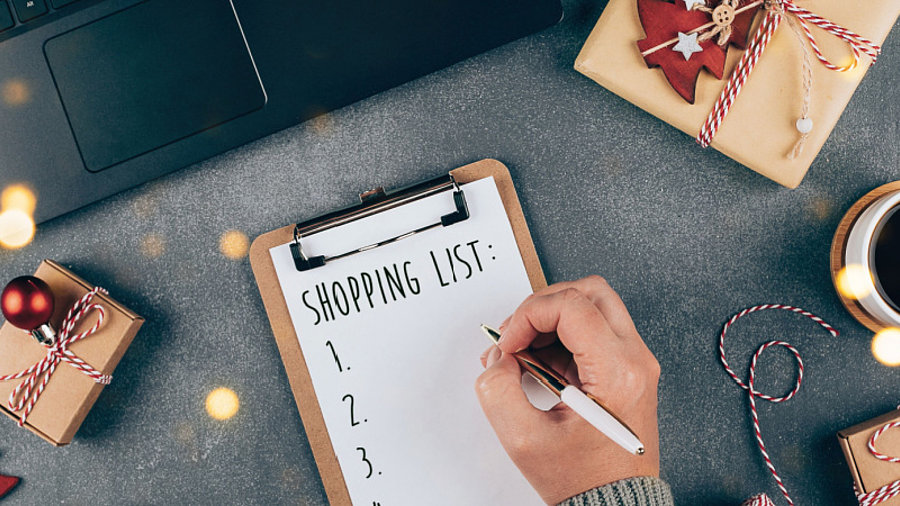 Person am Laptop schreibt Einkaufsliste, Weihnachtspakete drumherum