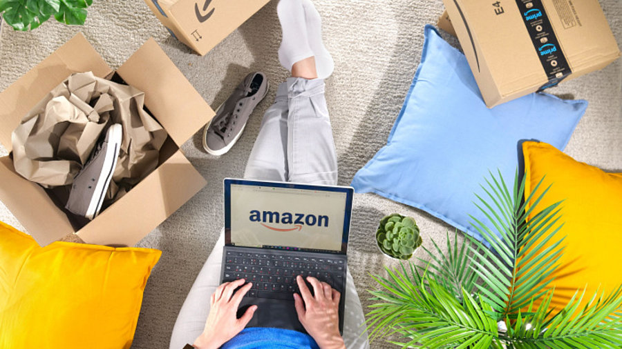 Stapel von Amazon Prime-Pakete, Frau mit Laptop