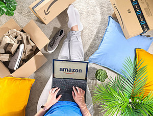 Stapel von Amazon Prime-Pakete, Frau mit Laptop