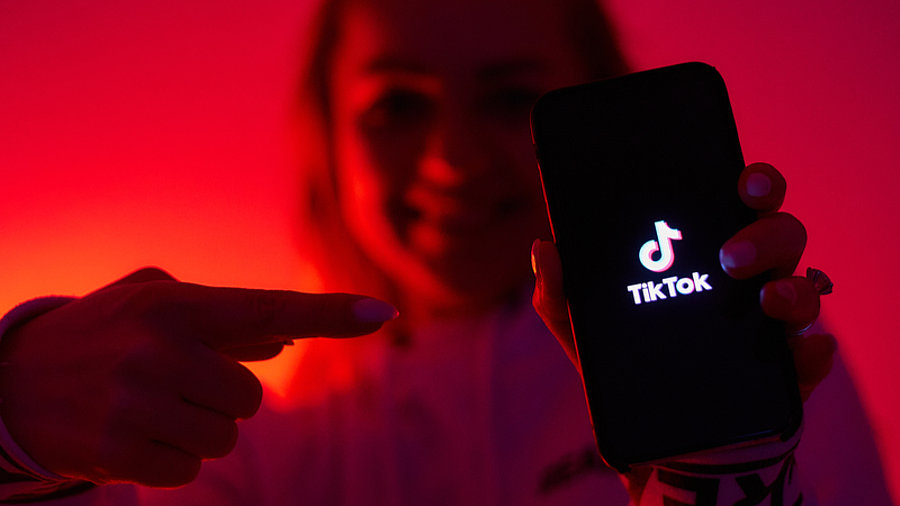 Frau zeigt auf Smartphone mit TikTok