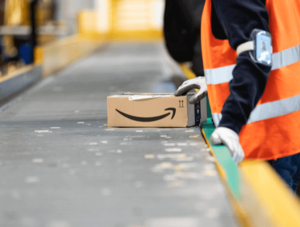 Amazon-Logistik-Mitarbeiter mit Paket an einem Fließband