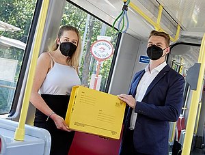 Zwei Leute halten Paket in der Straßenbahn fest