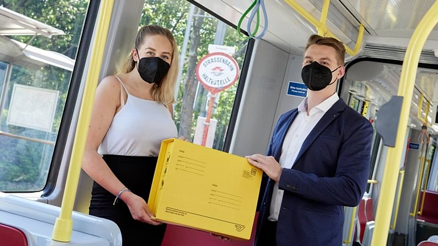 Zwei Leute halten Paket in der Straßenbahn fest