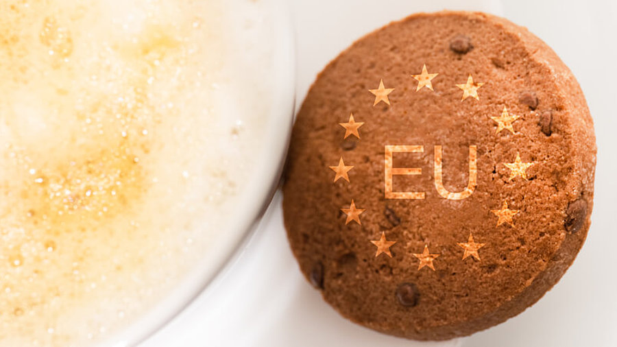 Keks mit der Aufschrift EU und Sternen liegt neben einer Tasse Kaffee